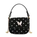 Small black crossbody handbag with white dot print, pink butterfly clasp, and gold chain strap - Black