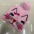 Pink children's knitted beanie with a folded cuff, playful cat face pattern and fluffy pom-pom - One Size (3-8 Years) / Cat Pink