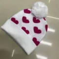 Children's white knitted beanie with magenta heart pattern, fluffy pom-pom and folded cuff - One Size (3-8 Years) / Heart White