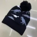 Children’s black knitted beanie with gray and white dinosaur pattern, folded cuff and pom-pom - One Size (3-8 Years) / Dino Black
