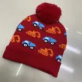 Red children's knitted beanie with blue and orange construction vehicle motifs and a red pom-pom - One Size (3-8 Years) / Vehicle Red