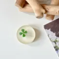 Bovenaanzicht van een ronde, matdoorzichtige telefoonhouder met een groen klavertjeviermotief - Glitter Elegant Geel