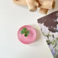 Bovenaanzicht van een rond roze harsobject met een groen klavertje dat erin is ingesloten - Glitter Bonenpasta Rood