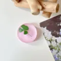Close-up van een matroze rond oppervlak met een groen klavermotief, gestyled op een wit tafelblad - Glinsterend Donkerroze