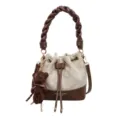 Front view of a cream quilted bucket bag with brown trim, braided handle and teddy bear charm - No Pendant / Off White