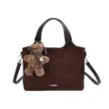 Front view of a brown suede-textured tote with dark handles and a plush bear charm on white - Brown