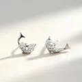Gros plan sur une paire de puces d’oreilles dauphin argentées serties de zircons blancs scintillants - Argent 990 / Or blanc