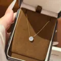 Gold-tone fine chain with a round clear stone pendant displayed in a brown velvet jewelry box - Six-Prong Round Style (Rhinestone)