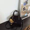 Black suede-look Boston bag with top handles, shoulder strap, gold-tone hardware and plush charm - With Pendant / Black
