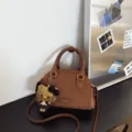 Sac Boston brun en PU aspect daim, avec poignées, bandoulière amovible et breloque chat en peluche - Marron