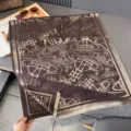 Flachaufnahme eines braun-beigen Schals mit wiederholten Planetenmotiven und Fransen am Rand - 185x65cm / Kaffeebraun