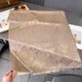 Flach ausgelegter taupefarbener Jacquard-Schal mit wiederholtem Muster und Fransen an den Kanten - 185x65cm / Camel