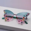Close-up of butterfly sunglasses with gradient lenses and colorful raised flower accents - Green to Pink Gradient