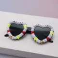 Close-up of MERRY CHRISTMAS beads with star, red, and gold accents on heart-shaped frames - Black