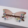 Close-up of brown gradient lenses with colorful glitter flower accents on rimless sunglasses - Tea Gradient
