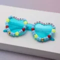 Close-up of turquoise party sunglasses with colorful beads and MERRY CHRISTMAS lettering - Sky Blue