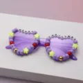 Close-up of purple frames decorated with colorful beads, star charms, and “MERRY CHRISTMAS” letters - Purple