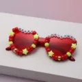 Close-up of red heart-shaped lenses with festive bead trim and “MERRY CHRISTMAS” lettering - Red
