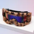Close-up of ski goggles with leopard-print faux-fur trim and a colorful mirrored lens on display - Black Frame Leopard Border