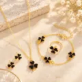 Flat lay of gold-tone chains with black four-leaf clover charms on a beige stone surface - Set / Black Clover