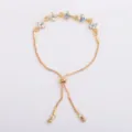Detail of a gold-tone bracelet with iridescent four-petal flower charms and a sliding clasp - AB Color (5326)