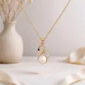 Close-up of a gold swan pendant with a round white pearl and sparkling stones on a fine chain - Gold Swan Necklace / Gold