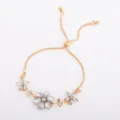 Gold-tone sliding chain bracelet with three clear crystal flowers, shown flat on white - Petal Style (5325) / Gold