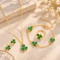 Gold-tone chains and jewelry pieces with green clover accents arranged on a warm stone surface - Green Clover