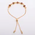 Gold-tone bracelet laid flat, showing brown four-petal flower links and an adjustable sliding clasp - Coffee