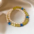 Bracciale a due fili su seta, con perle avorio, giallo-verdi e blu, e piccoli distanziatori dorati - Bracciale Doppio Filo Perle Vetro Occhio di Gatto