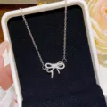 Close-up of a sparkling silver bow pendant necklace displayed on a black velvet jewelry box - Bowknot Pendant (X392) / Silver