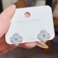 Close-up of two sparkling four-leaf clover earrings with clear stones on a white S925 jewelry card - White Clover (E0161)