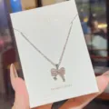 Close-up of a silver-tone bow pendant necklace with sparkling stones, displayed on a white card - Bowknot Pendant Style (X508) / 1-Piece Pack / Silver