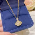 Close-up of a gold chain and sparkling fan-shaped pendant with clear stones in a navy velvet box - Gold