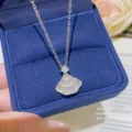 Close-up of a fan-shaped crystal pendant and fine chain displayed in a navy velvet jewelry box - Silver