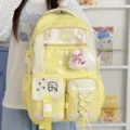 Yellow student backpack with clear display panel, plaid accents, pockets and plush charm - Yellow