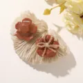 Close-up of two glossy brown resin flower accessories, one accented with clear bead strands - Brown Five-Petal Flower