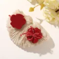 Close-up of two glossy red resin flowers, one with red bead accents, on a textured display - Red Five-Petal Flower