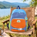 Sac à dos enfant bleu et orange avec poches latérales vert citron, posé sur une chaise de camping - Bleu