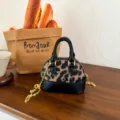 Mini sac coquillage à imprimé léopard, bordure en cuir noir et bandoulière chaîne dorée - Noir
