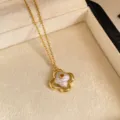 Primer plano de un colgante floral calado dorado, con centro perlado y una piedra naranja decorativa - Collar / Collar-Dorado-Blanco