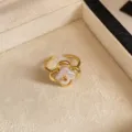 Primer plano de un anillo abierto dorado con flor de perla, dentro de un joyero de terciopelo crema - Anillo / Anillo Dorado Blanco