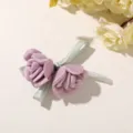 Zwei mauvefarbene Satinrosen mit hellgrünen Schleifen, flach auf einer hellen Tischfläche arrangiert - Lila