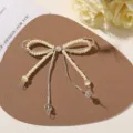 Close-up of an ivory pearl-beaded bow with silver tube accents and a central pearl on leather - Yellow