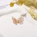 Detail van een transparant roze vlindercharm met glitters en gele ruitvormige middensteen - 1 Stuk/Verpakking / Champagnegoud
