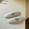 Par de pinzas para el pelo de tela blanca con lunares negros, lazos plateados y detalle de strass - Blanco / Juego de 2 Piezas