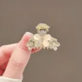 Close-up of a gold flower claw clip with milky cat-eye petals and sparkling rhinestone accents - Exquisite Flower Rhinestone / No Specification / Gold