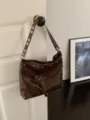 Brown faux-leather bag hanging from a door, with silver studs, eyelet strap and drawstring tassel - Brown
