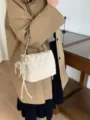 Cream quilted bag worn over a coat, with a chain strap, drawstring ties and pearl charm. - With Pendant / Off White