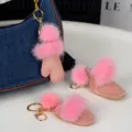 Gros plan sur la fourrure rose des breloques gant et bottines, avec des mousquetons dorés - Rose